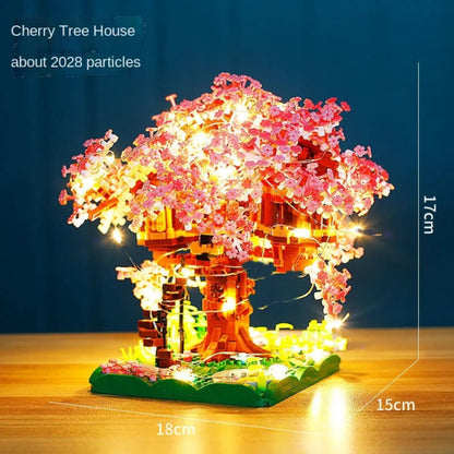 Cherry tree house model with LED lights on a wooden surface and dark blue background