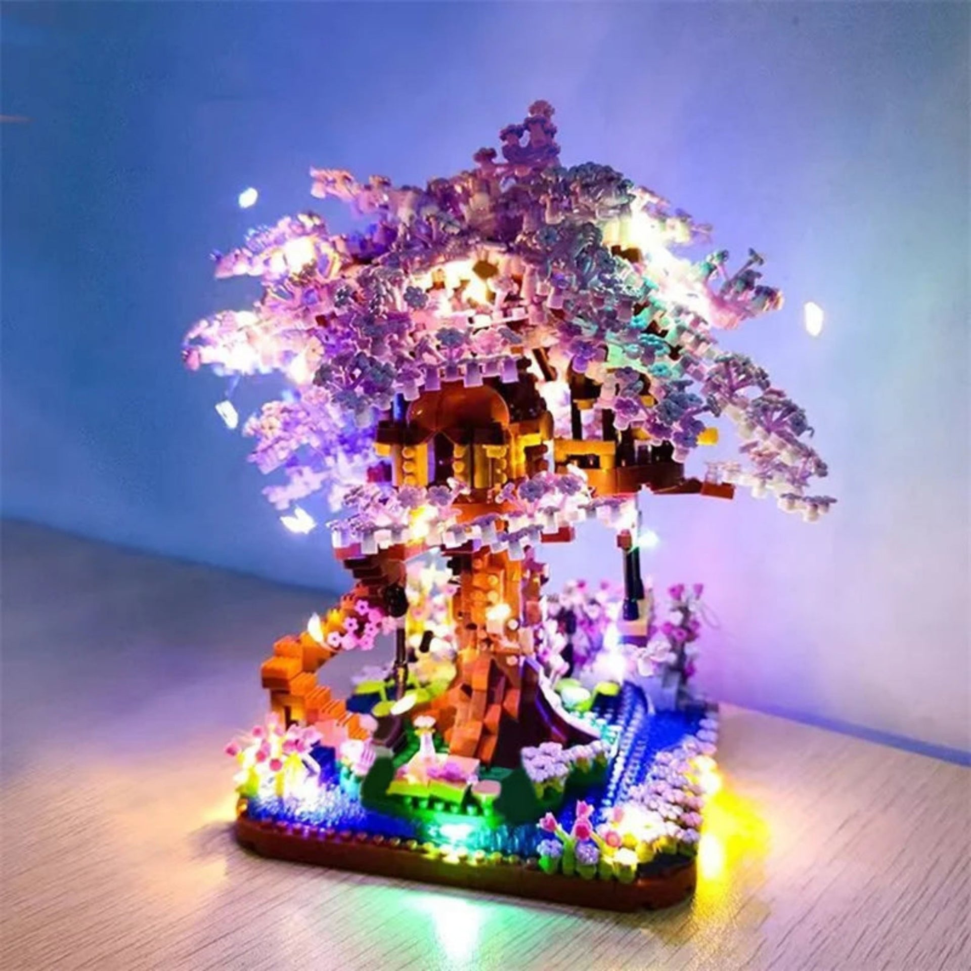 Colorful treehouse model with LED lights on a wooden surface