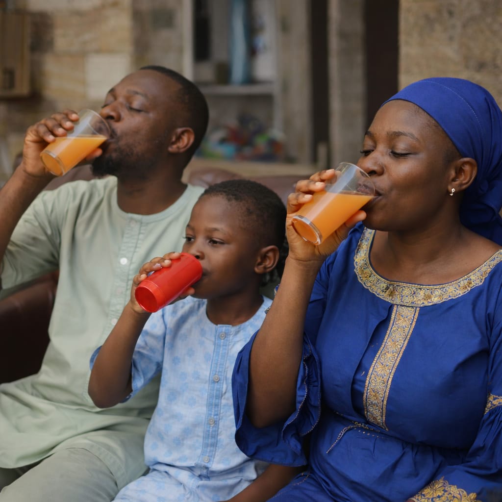 A family of three, including a father, mother, and child, sitting together and drinking the Electrokick ORS.