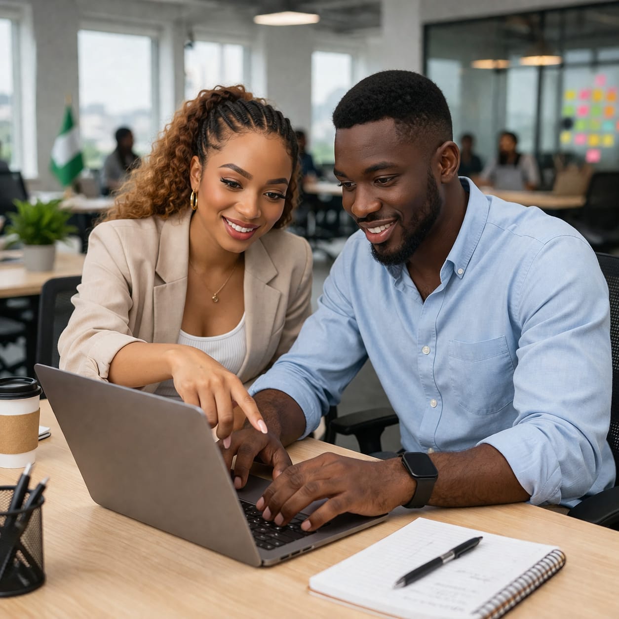 Two people working together on a laptop in an office setting