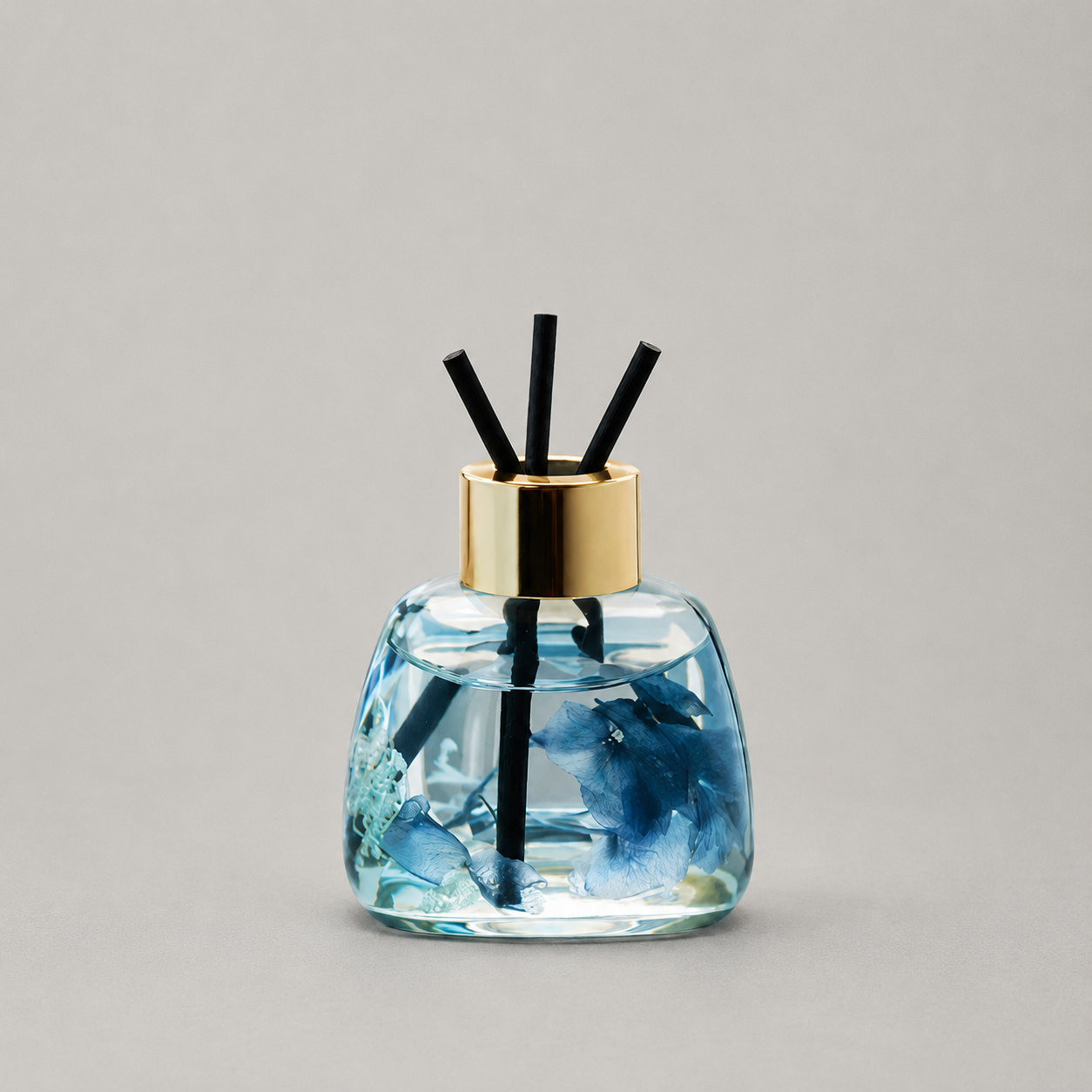 Decorative diffuser with blue design and gold cap on a gray background
