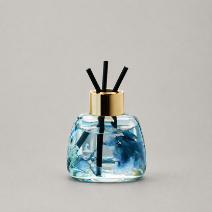 Decorative diffuser with blue design and gold cap on a gray background