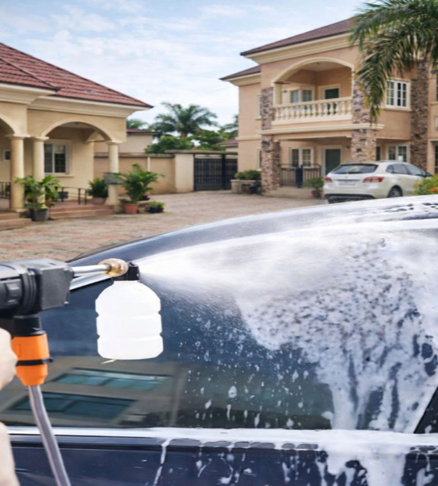 Car being washed with a pressure washer in front of a house