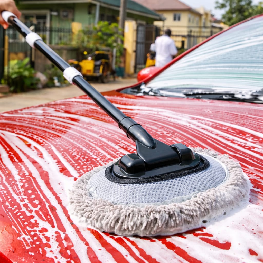 Car cleaning tool scrubbing a red car with soap suds.