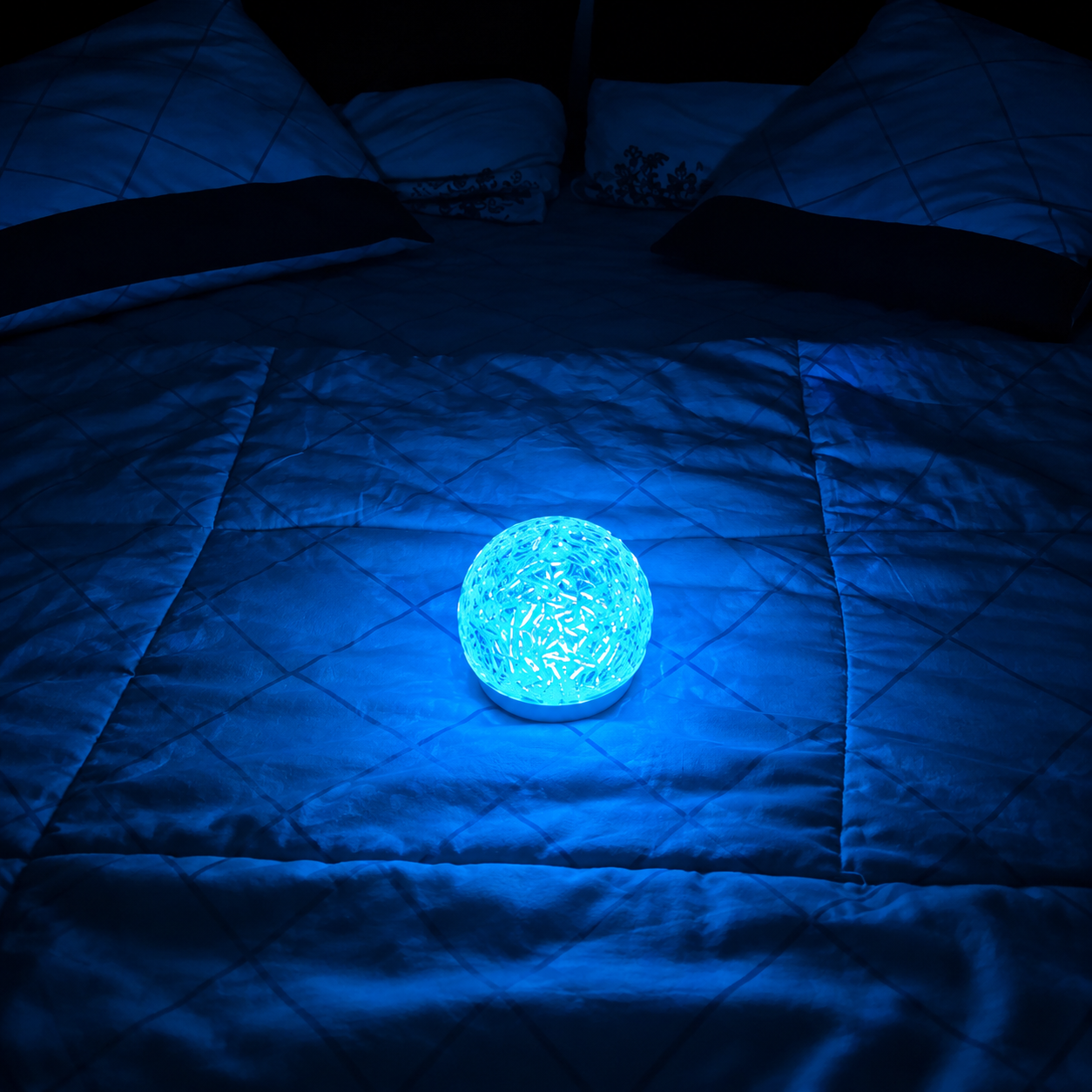 dome shape aurora galaxy projector glowing under a blue light on a bed