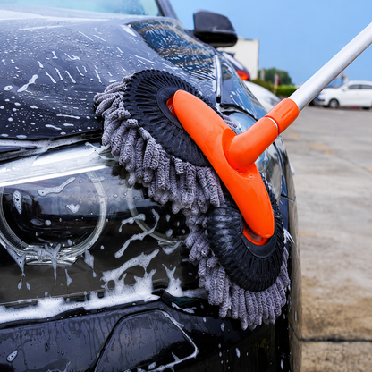 Car cleaning brush with gray bristle brush and orange handle on a car in a parking lot.
