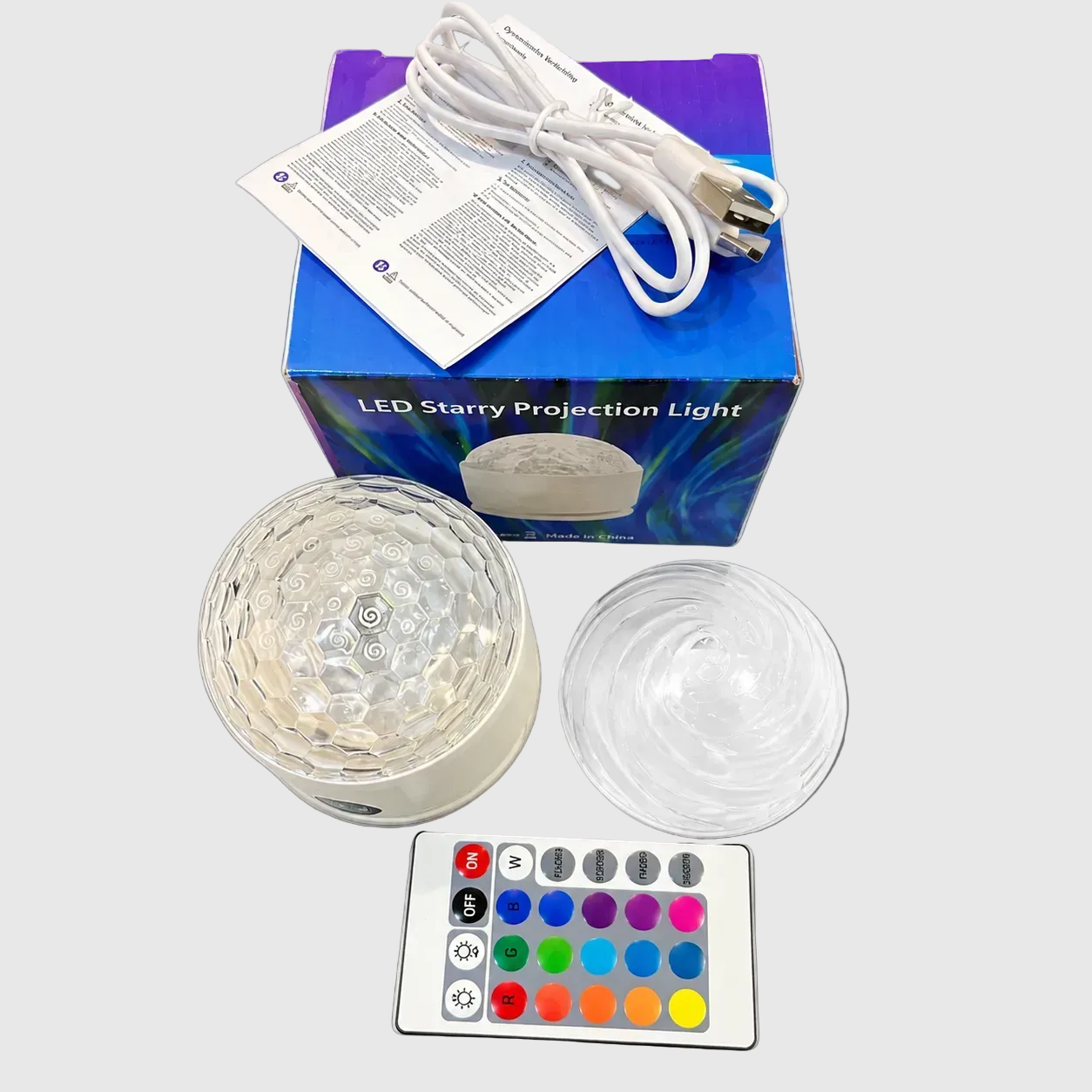 honeycomb_and_spira_design LED starry projection light with remote control, packaging, and cable on a white background