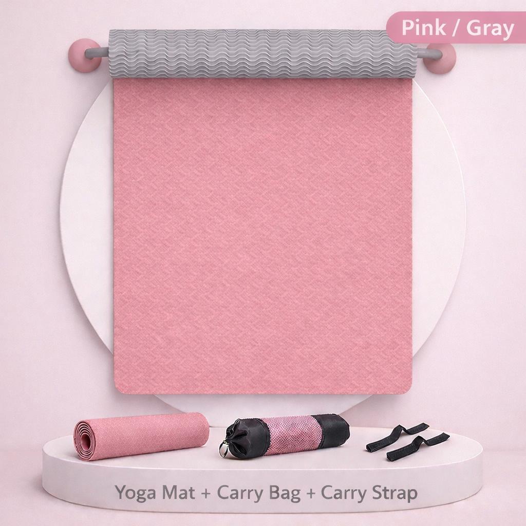 Pink yoga mat with gray top, black carry bag, and straps on a white background