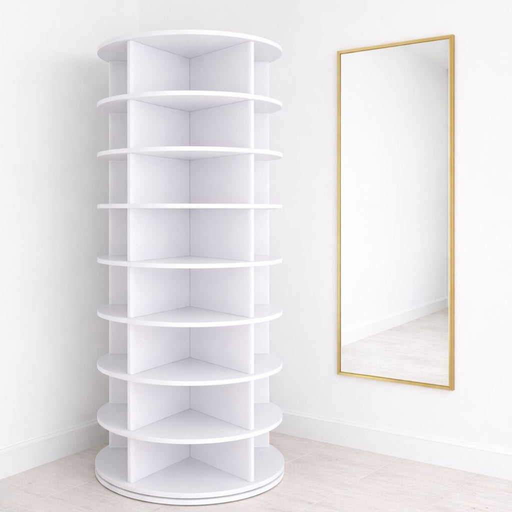 White corner rotating shoe rack next to a gold-framed mirror on a white wall.